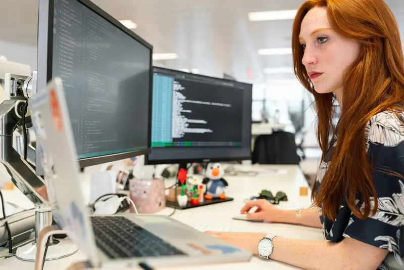 Software developer working with code on two monitors